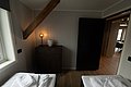 Gemütliches Schlafzimmer in Nordland, Norwegen: Zwei Betten, warme Beleuchtung, rustikaler Holzbalken, modernes Interieur. Ideal für erholsamen Angelurlaub. Entspannung und Komfort in malerischer Umgebung.