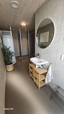 Modernes Badezimmer in Hitra, Norwegen, mit hellem Holzinterieur, rundem Spiegel und eleganter Einrichtung. Ideal für komfortable Angelurlaube. Moderne Ausstattung und stilvolles Design versprechen Entspannung nach einem erfolgreichen Angeltag.