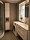 Modernes Badezimmer auf Hitra, Norwegen, mit Waschmaschine, Waschbecken und Duschkabine. Helle Einrichtung, ideal für Angelurlaube – komfortabel und praktisch. Perfekte Basis für Abenteuer und Entspannung in der idyllischen norwegischen Natur.