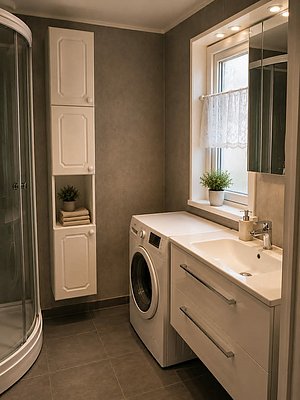 Modernes Badezimmer auf Hitra, Norwegen, mit Waschmaschine, Waschbecken und Duschkabine. Helle Einrichtung, ideal für Angelurlaube – komfortabel und praktisch. Perfekte Basis für Abenteuer und Entspannung in der idyllischen norwegischen Natur.