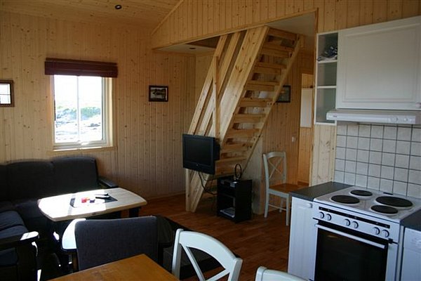 Gemütliches Ferienhaus in Nordland, Norwegen, mit Holzinterieur, Küche, Sitzecke und Treppe. Ideal für Angelreisen, bietet es Ruhe und Komfort nahe der beeindruckenden Naturkulisse der Region. Perfekt für entspannte Abende nach erfolgreichen Angelausflügen.