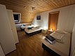 Ein gemütliches Schlafzimmer mit drei Einzelbetten, Holzboden und Vertäfelung. Nachtlichter sorgen für sanfte Beleuchtung. Perfekt für erholsame Nächte nach einem erfolgreichen Angelabenteuer in der Region Hitra, Norwegen.