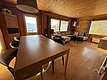 Gemütliches Wohnzimmer in einer Holzhütte auf Hitra, Norwegen. Helle Einrichtung, großer Esstisch, bequeme Sofaecke. Fantastischer Ausblick auf den Fjord durch große Fenster. Ideal für entspannte Angelurlaube und naturnahe Erholung.