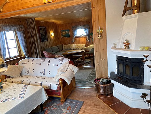 Gemütliche norwegische Ferienhütte in Hitra mit rustikalem Holzwänden, Kamin und einladenden Sofas. Perfekt für Angelreisende, die nach einem erfolgreichen Tag im Freien Entspannung suchen. Ideal für einen erholsamen Angelurlaub in Norwegens wilder Natur.