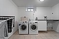 Heller Hauswirtschaftsraum in Nord-Norwegen mit Waschmaschine, Trockner und Waschbecken. Handtücher und Waschmittel ergänzen die funktionale Einrichtung. Perfekt für längere Angelaufenthalte.