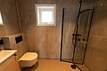 Modernes Badezimmer in Nordland, Norwegen, mit eleganter Dusche, hochmodernem WC und stilvollen Holzwänden. Ideal für Angelreisen mit Komfort. Helles Fenster sorgt für natürliches Licht. Perfekte Kombination aus Funktionalität und skandinavischem Design.