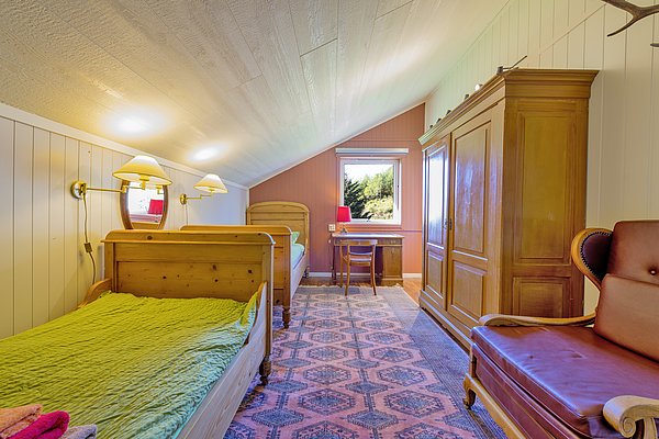 Gemütliches Zimmer in Nordland, Norwegen, mit rustikalen Holzmöbeln und warmem Licht. Großes Fenster bietet Aussicht auf die Natur. Ideal für Erholungssuchende und Angler auf Angelreisen. Perfekte Kombination aus Komfort und Abenteuerlust.