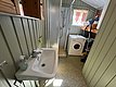 Gemütliches Badezimmer in Hitra, Norwegen, mit Dusche, Waschbecken und Waschmaschine. Ideal für Anglerreisen, um Komfort und Bequemlichkeit nach einem erfolgreichen Angelausflug zu genießen. Perfekte Mischung aus Funktionalität und rustikalem Charme.