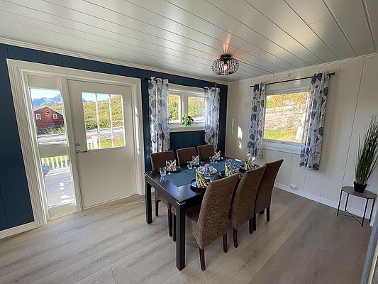 Gemütliches Esszimmer in Nord-Norwegen mit elegant gedecktem Tisch, großen Fenstern und Blick auf die malerische Landschaft. Helle Holzböden und stilvolle Dekoration schaffen eine einladende Atmosphäre für gesellige Runden in einer naturnahen Umgebung.