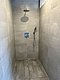 Moderne, geräumige Dusche mit grauen Fliesen und Regenduschkopf in Nord-Norwegen. Ideal für Entspannung nach einem erfolgreichen Angeltag. Hochwertiges Design für optimalen Komfort.