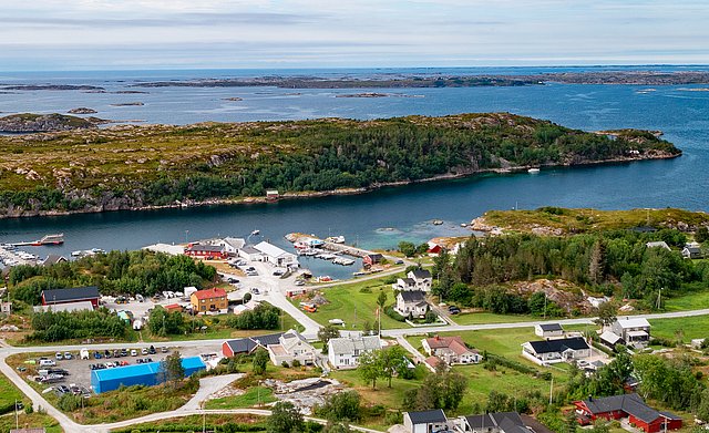 Luftaufnahme von Hitra, Norwegen: Küstenort mit bunten Gebäuden, malerischen Landschaften und fjordähnlichen Gewässern, ideal für Angelreisen. Die Insel bietet beeindruckende Naturkulissen und hervorragende Möglichkeiten für Meeresangeln und Entspannung.