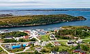 Luftaufnahme von Hitra, Norwegen: Küstenort mit bunten Gebäuden, malerischen Landschaften und fjordähnlichen Gewässern, ideal für Angelreisen. Die Insel bietet beeindruckende Naturkulissen und hervorragende Möglichkeiten für Meeresangeln und Entspannung.