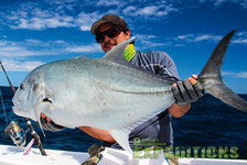 Ein Angler hält einen großen Fisch unter blauem Himmel an der Küste Süd-Norwegens. Perfektes Ziel für Angelreisen mit spannenden Fangchancen. Ideal für Meeressportangler, die Abenteuer in malerischer Natur suchen.