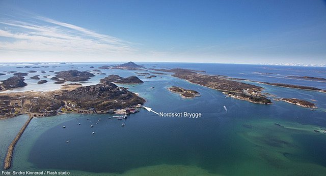 Luftaufnahme von Nordland, Norwegen: Malerische Küstenlandschaft mit Inseln und Fjorden. Nordskot Brygge als markanter Punkt. Perfekt für Angelreisen und Naturerlebnisse. Klarer blauer Himmel und weite Meeresblicke. Ideal für Abenteurer und Erholungssuchende.