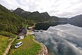 Klares Wasser des norwegischen Fjords in Nord-Norwegen, umgeben von grünen Bergen und einer abgelegenen Hütte. Perfektes Reiseziel für Angelabenteuer und Naturerlebnisse. Ideal für Angelreisen und erholsame Urlaube abseits der Massen.