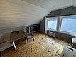 Gemütlicher Raum mit Holzboden, Tisch und Stühlen, großen Fenstern mit Blick auf das klare Wasser von Hitra, Norwegen. Perfekter Rückzugsort für Angler auf Angelreise, um Natur und Entspannung zu genießen.