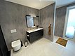 Modernes Badezimmer in Hitra, Norwegen: Graue Wände, eleganter Waschtisch, wandhängende Toilette, große Fenster für Tageslicht. Ideal für entspannten Angelurlaub. Skandinavisches Design für Komfort und Stil. Perfekte Unterkunft für Abenteuer und Erholung.