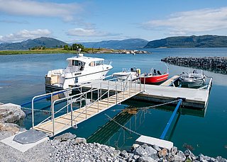Kleiner Hafen in Südwest-Norwegen mit festgemachten Booten an einem Steg, umgeben von zerklüfteten Bergen und ruhigem Wasser. Perfekter Ausgangspunkt für Angelabenteuer in unberührter Natur.
