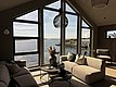 Gemütliches Wohnzimmer in Südwest-Norwegen mit Panoramafenstern, die den Blick auf das malerische Meer und die Küste freigeben. Moderne Einrichtung sorgt für entspannte Urlaubsatmosphäre. Perfekt für eine Angelreise in atemberaubender Natur.