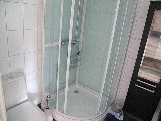 Kompaktes, modernes Badezimmer mit Dusche, WC und Stauraum. Helle Fliesen und klare Struktur bieten Komfort. Ideal für Angler auf Reisen in Nordland, Norwegen. Entspannung nach einem erfolgreichen Tag beim Meeresangeln.