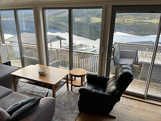Gemütliches Wohnzimmer mit Panoramablick auf norwegischen Fjord. Gelegene Terrasse mit gemütlichen Sitzmöglichkeiten und malerischem Seeblick in Südwest-Norwegen. Perfekte Unterkunft für entspannenden Angelurlaub. Ideal für Naturliebhaber und Erholungssuchende.