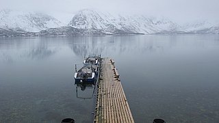 Kühler Bergsee mit schneebedeckten Bergen im Hintergrund, ruhiger Steg mit zwei Booten, ideal für Angelabenteuer in der malerischen Tuna Coast von Panama. Perfekter Ort für Naturliebhaber und Angelfans.