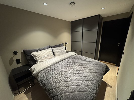 Gemütliches Schlafzimmer in Südwest-Norwegen mit einem großen Bett, modernen Einbauschränken und stilvoller Beleuchtung. Perfekt für erholsame Nächte nach einem erfolgreichen Angelurlaub in atemberaubender Natur.