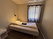 Gemütliches, schlicht eingerichtetes Schlafzimmer in Hitra, Norwegen. Einzelbett mit Leselampe, Fenster mit Vorhang. Ideal für Angelurlaub, Ruhe und Entspannung in der Natur. Entdecke die fischreichen Gewässer der Umgebung.