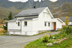 Weißes Holzhaus in Nord-Norwegen, umgeben von steilen Bergen und herbstlicher Landschaft. Ideal für Angelreisen und Naturerlebnisse. Ruhige Umgebung lädt zum Entspannen ein. Perfekter Ausgangspunkt für Abenteuer und Angelausflüge.