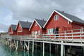 Rote Holzhäuser auf Stelzen in Nordland, Norwegen, am Wasser. Perfekter Ausgangspunkt für Angelabenteuer im Norden, umgeben von malerischer Landschaft. Ideal für Angelreisen und Naturliebhaber.