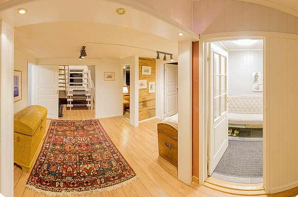 Ein gemütlicher, skandinavischer Innenraum in Nordland, Norwegen, mit Holzfußboden, orientalischem Teppich und einladendem Sofa. Stilvolle, helle Einrichtung für entspannte Anglerunterkünfte. Ideal für Angelurlauber in nordischer Umgebung.