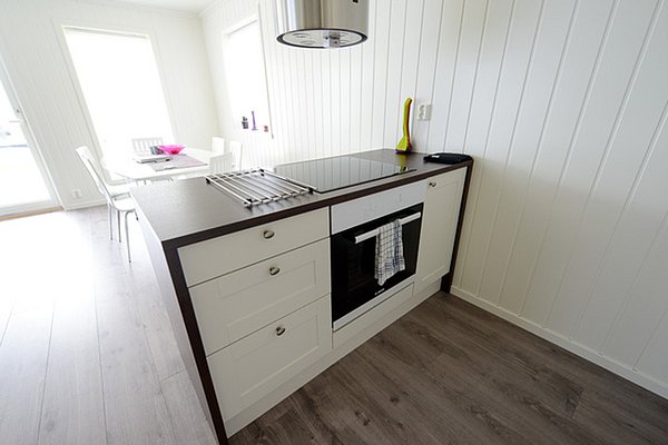 Moderne, helle Küche in Nordland, Norwegen, mit weißen Wänden, Holzboden, Kochinsel und Esstisch. Ideal für einen entspannten Angelurlaub mit komfortabler Selbstversorgung. Perfekte Basis für ein Abenteuer im hohen Norden.