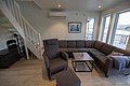 Gemütliches Ferienhaus auf Hitra, Norwegen. Modernes Wohnzimmer mit großen Fenstern, Ecksofa, Sessel und Treppe. Helle, einladende Atmosphäre mit schöner Aussicht auf die umliegende Natur. Perfekt für entspannte Angelurlaube.