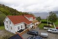 Ein gemütliches, traditionelles, weißes Haus mit roten Ziegeldach, umgeben von grüner Natur und malerischem Blick auf das Meer in Hitra, Norwegen. Perfekt für einen entspannten Angelurlaub in skandinavischer Idylle.
