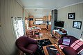 Gemütliches Wohnzimmer in Nord-Norwegen, warm dekoriert mit Holzmöbeln, bequemen Sesseln, Esstisch und TV. Perfekt für entspannte Angelurlaube in skandinavischer Atmosphäre. Ideal für Meeresangler auf Abenteuerreise.