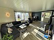 Helles, gemütliches Wohnzimmer in Nord-Norwegen mit großer Eckcouch, Sessel, Fernseher, Kamin und Tageslicht. Ideal für Entspannung nach einem Angeltag in atemberaubender Naturkulisse. Perfekte Unterkunft für Angelurlaub in Skandinavien.
