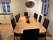 Gemütlicher Essbereich in Nord-Norwegen: Großer Holztisch, schwarze Stühle, Küchenzeile, Spiegel, rustikaler Stil. Ideal für geselliges Beisammensein nach abenteuerlichen Angelreisen im hohen Norden. Perfekter Ort für Erholung und Gemeinschaft.