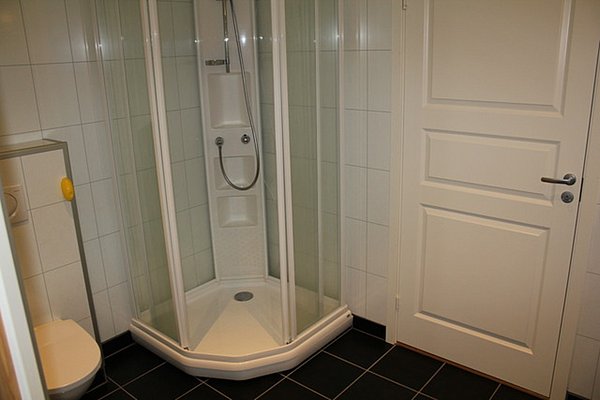Modernes Badezimmer in Nord-Norwegen mit Duschkabine und weißen Fliesen. Ideal für Angeltouren, um nach einem langen Tag auf dem Wasser zu entspannen. Perfekte Ausstattung für Komfort und Erholung.
