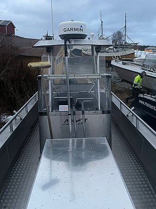 Aluminium-Angelboot im Hafen von Südwest-Norwegen, ausgestattet mit Garmin-Technologie. Ideal für Meeresangeln und Abenteuer in skandinavischen Gewässern. Wetterbedeckte Boote und Winteratmosphäre verstärken die maritime Stimmung.