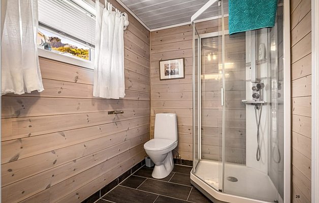 Helles Badezimmer in Südwest-Norwegen, mit Holzwänden, moderner Dusche und weißen Vorhängen. Gemütliche, natürliche Atmosphäre ideal für Erholung nach einem abenteuerlichen Angelurlaub. Perfektes Refugium für Angler und Naturliebhaber in der Region.