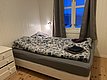Gemütliches Schlafzimmer in Nord-Norwegen mit Doppelbett, Blumenbettwäsche und Fensterblick auf verschneite Landschaft. Ideal für erholsamen Angelurlaub in skandinavischer Natur. Rustikales Holzdesign ergänzt den Komfort für Angler auf der Suche nach Abenteuer.