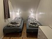 Gemütliches Schlafzimmer in Nord-Norwegen mit zwei Einzelbetten, stilvoller Holzvertäfelung und funktionalem Stauraum. Perfekt für Angelurlauber, die Ruhe und Komfort nach einem erlebnisreichen Tag am Wasser suchen. Petri Heil – sorglos angeln weltweit!