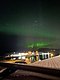 Aurora borealis leuchtet über einem malerischen Hafen in der Region Hitra, Norwegen. Eine beeindruckende Kombination aus Nordlichtern und Küstenlandschaft, ideal für Fotografen und Angelreisende. Entdecke Meeresangeln vor spektakulären Naturkulissen.