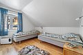 Gemütliches Schlafzimmer in Nord-Norwegen mit zwei Einzelbetten, Holzfußboden und großem Fenster. Außenblick auf verschneite Landschaft und Fjord. Ideal für Angelreisen und naturverbundene Erholung in skandinavischem Ambiente.