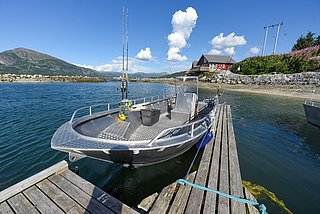 Fischereiboot in Nordland, Norwegen: Aluminiumboot am Holzsteg mit Angelruten, klare See und Berge im Hintergrund, ideale Bedingungen für Angelreisen. Perfekter Ort für Naturliebhaber und Angler, um die Schönheit der nordischen Landschaft zu genießen.