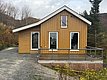 Gemütliches Holzhäuschen in Nordland, Norwegen, umgeben von herbstlicher Natur. Ideal für entspannte Angelurlaube. Große Fenster und Veranda bieten fantastische Aussichten auf die wilde Landschaft. Perfekter Rückzugsort für Abenteuer und Erholung.