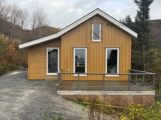 Gemütliches Holzhäuschen in Nordland, Norwegen, umgeben von herbstlicher Natur. Ideal für entspannte Angelurlaube. Große Fenster und Veranda bieten fantastische Aussichten auf die wilde Landschaft. Perfekter Rückzugsort für Abenteuer und Erholung.