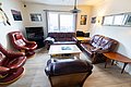 Einladendes Wohnzimmer in Nordland, Norwegen. Gemütliche Ledersofas, Holzboden, TV und Wandbilder, kreative Dekoration mit Fischmotiv. Perfekt für erholsame Abende nach einem erfolgreichen Angeltag. Skandinavisches Ambiente und entspannte Atmosphäre.