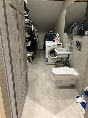 Hauswirtschaftsraum mit Waschmaschine, Trockner und Bügelbrett, moderner Stil. Funktionaler Bereich ideal für erholsamen Angelurlaub in Nord-Norwegen. Praktische Einrichtung für komfortables Reisen, Wäschestapel im Regal.