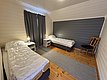 Gemütliches Schlafzimmer in Hitra, Norwegen, mit zwei Einzelbetten, heller Holzvertäfelung und modernem Design. Perfektes Angelurlaub-Domizil in ruhiger Umgebung. Ideal für Erholung nach erfolgreicher Angeltour.